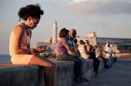 In this March 11, 2014 photo, a woman uses her cellphone as she sits on the Malecon in Havana, Cuba. The U.S. Agency for International Development masterminded the creation of a "Cuban Twitter," a communications network designed to undermine the communist government in Cuba, built with secret shell companies and financed through foreign banks, The Associated Press has learned. The project, which lasted more than two years and drew tens of thousands of subscribers, sought to evade Cuba's stranglehold on the Internet with a primitive social media platform. (AP Photo/Franklin Reyes)