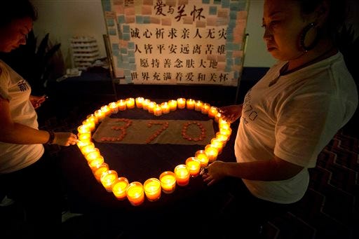 Relatives of Chinese passengers on board the Malaysia Airlines Flight MH370 lit candles in a prayer room in Beijing, China, Friday, April 4, 2014. Two ships with sophisticated equipment for searching underwater zeroed in Friday on a remote stretch of the Indian Ocean in a desperate hunt for the missing jet's black boxes, whose batteries will soon run out. Chinese characters for words of consolations are seen at top. (AP Photo/Ng Han Guan)
