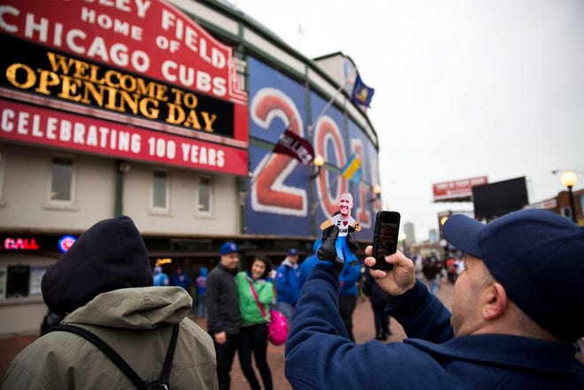 Mark Maroon, of Aurora, Ill., takes a picture of a cutout of his brother-in-law before the Chicago Cubs home opener against the Philadelphia Phillies on Friday, April 4, 2014, in Chicago.