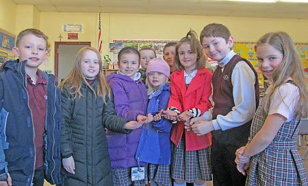 Second-grade students at SHS show off the handmade rosary beads they created for the SHS auction, to be held Saturday night.