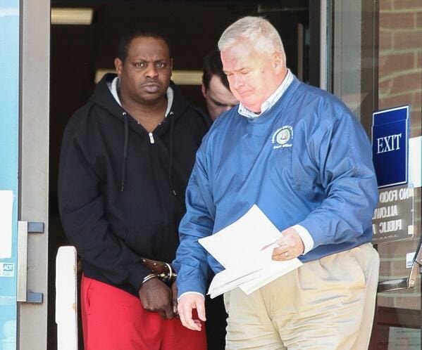Darnell Austin 39, left, is led from court in Portsmouth on Thursday by police officer Michael Ronchi.