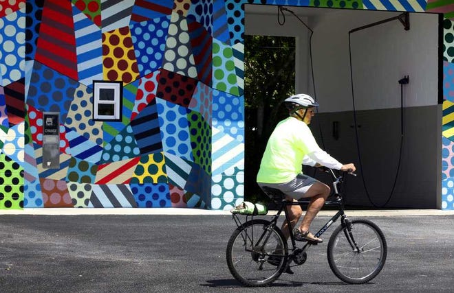 DARON.DEAN@STAUGUSTINE.COM A bicyclist passes the newly painted car wash at 306 Anastasia Blvd. on Thursday, April 3, 2014. Acclaimed New York City artist Jason Woodside completed the pop art mural recently.