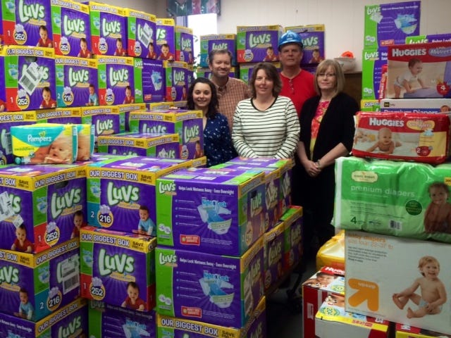 Local Weyerhaeuser employees stand with some of the 53,885 diapers they collected as part of a non-profit project they finished this week. Pictured from back left are mill manager and Vice President John Ashley and first place winner Bryan Ipock, and, from front left, lead event coordinator Amy Mills and second place winners Susan Sugg and Cheryl Riggs.