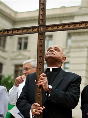 FILE - In this April 6, 2012, file photo, Rev. Wilton Gregory, the Archbishop of Atlanta holds a cross during the 32nd annual Good Friday Pilgrimage at Hurt Park in Atlanta. Gregory apologized Monday, March 31, 2014, for building a $2.2 million mansion for himself, a decision criticized by local Catholics who cited the example of austerity set by the new pope. (AP Photo/Atlanta Journal-Constitution, Jason Getz, File)