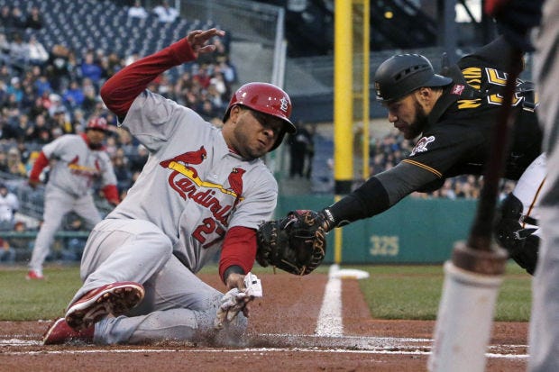 The Cardinals' Jhonny Peralta (27) slides safely around the attempted tag of  Pirates catcher Russell Martin during the first inning in Pittsburgh on Saturday. Peralta scored from third on a sacrifice fly by Allen Craig.
