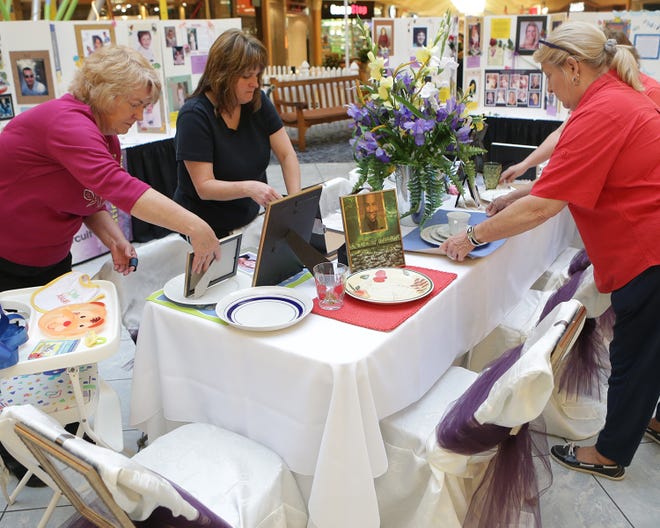 Charlotte Greathouse, from left, Jennifer Bates and Gail Bradbury set up the ninth annual Missing Place at the Table ceremony at the Panama City Mall on Sunday. The event will take place Monday.