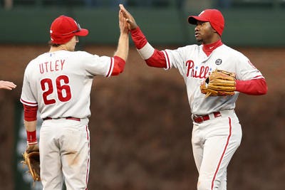 Philadelphia Phillies second baseman Chase Utley, left, and left fielder Domonic Brown, right, celebrate after defeating the Chicago Cubs 7-2 in a baseball game on Friday, April 4, 2014, in Chicago. (AP Photo/Andrew A. Nelles)