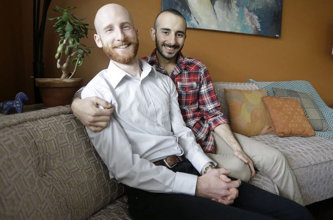 In this April 3, 2014, photo, Derek Kitchen, left, and Moudi Sbeity sit on their couch at their home, in Salt Lake City. The young couple that has become the face of gay marriage in Utah is an unlikely pair for the role. Kitchen and Sbeity were both raised in conservative religious families that shun gays, Kitchen in a Mormon home in Utah and Sbeity in a Muslim family in Lebanon. They each came out when they were 16 years old, worlds apart, and met six years later in college in Utah. They chose to become one of three couples as plaintiffs in the lawsuit challenging Utah's same-sex marriage to publicly push back against religions that oppress gays and lesbians. (AP Photo/Rick Bowmer)