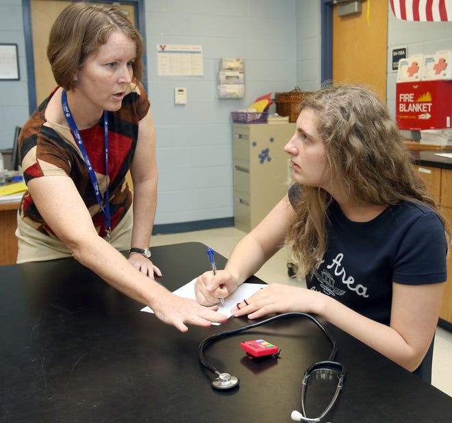 Candi Roy, left, talks with Galina Abdelaziz, 16, a junior, in the Biology III class during a lesson about heart rate at Vanguard High School in Ocala on Monday.
