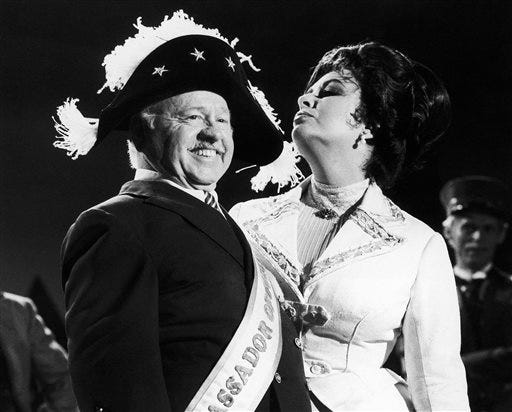 FILE - In this Thursday, Aug. 27, 1981, file photo, veteran comic Mickey Rooney wears a Napoleonic-era hat as he tapes an “I love New York” television commercial with British-American actress Elizabeth Taylor, in New York. Rooney, a Hollywood legend whose career spanned more than 80 years, has died. He was 93. Los Angeles Police Commander Andrew Smith said that Rooney was with his family when he died Sunday, April 6, 2014, at his North Hollywood home. (AP Photo/GPB, File)