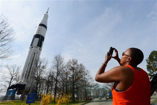 Kam Brown photographs the Saturn 1B Rocket at the Alabama Welcome Center on Interstate 65 on April 2, 2014 in Ardmore, Ala. The paint is faded, and black mold and algae cover the bottom. Birds use the rocket's crevices for nests, and their droppings are everywhere. The U.S. Space and Rocket Center in Huntsville is working with the Alabama Department of Transportation to get it pressure-washed and painted this summer. The state Tourism Department will fund the project. (AP Photo/The Decatur Daily, Gary Cosby Jr.)