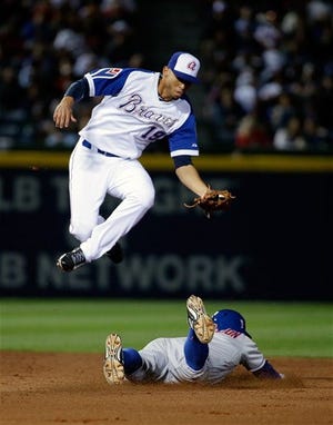 Atlanta Braves shortstop Andrelton Simmons, left, jumps over New York Mets' Curtis Granderson as he steals second base in the sixth inning of baseball game, Tuesday, April 8, 2014, in Atlanta.