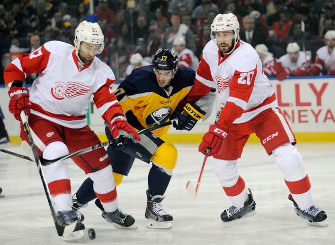 Detroit Red Wings defenseman Kyle Quincy (27) battles for the puck with Buffalo Sabres center Torrey Mitchell (17) as Red Wings left winger Drew Miller (20) defends during the first period in Buffalo, N.Y. on Tuesday. (AP Photo/Gary Wiepert)