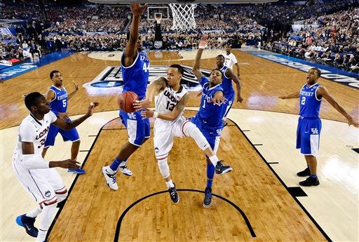 Connecticut guard Shabazz Napier (13) passes around Kentucky center Dakari Johnson (44) to center Amida Brimah (35) as guard James Young (1) helps during the first half of the NCAA Final Four tournament college basketball championship game Monday, April 7, 2014, in Arlington, Texas.