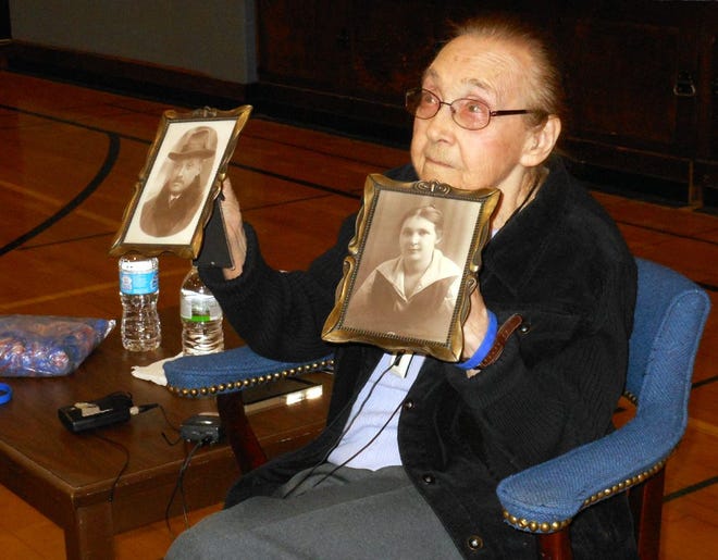Helen Sperling, a survivor of the Holocaust, holds up pictures of her parents before talking to students at Poland Central School on Monday. Both her parents perished at death camps along with six million others as part of the Holocaust. TIMES PHOTO/STEPHANIE SORRELL-WHITE