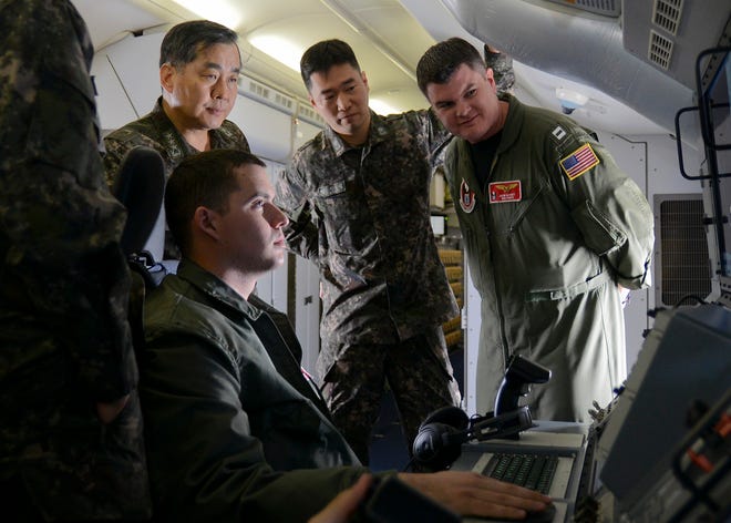 Vice Adm. Jung Ho Sup, commander of the Republic of Korea Fleet, watches AWO3 Cody Wojasinski, attached to VP-16, adjust equipment on a P-8A Poseidon aircraft during a distinguished visitor flight with senior members of the Republic of Korea navy.