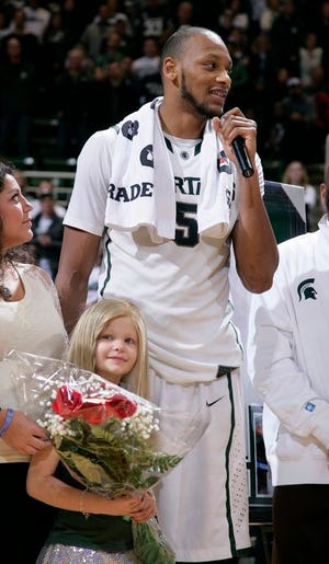 In this March 6, 2014 file photo, Michigan State senior Adreian Payne addresses the crowd during a senior day ceremony as he stands with his guest, Lacey Holsworth, who is battling cancer, following an NCAA college basketball game against Iowa, in East Lansing, Mich. The father of 8-year-old Lacey Holsworth, who befriended Michigan State basketball star Adreian Payne says his daughter has died. Matt Holsworth says Lacey Holsworth died at their St. Johns, Mich., home late Tuesday, April 8, 2014 "with her mommy and daddy holding her in their arms."
