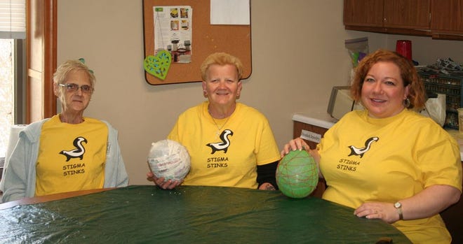 Ivy Combs, Karen Wiitanen and River's Edge Drop-In Center Director Carol Foster make papier-mâché Easter eggs in the center's craft room, and don their “Stigma Stinks” T-shirts.