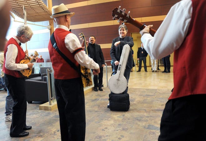 Members of the Central Illinois Banjo Club play "Five Foot Two, Eyes of Blue" for 15-time Grammy Award winning banjo player Bela Fleck shortly after his arrival at the Peoria airport Thursday afternoon. Behind Fleck is Peoria Symphony Orchesta director George Stelluto.