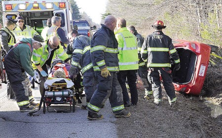 Emergency workers remove a woman from an overturned vehicle after a crash on Route 236 in Eliot on Wednesday before transporting her to the hospital during rush-hour traffic.