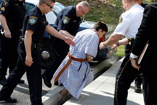 Alex Hribal, the suspect in the multiple stabbings at the Franklin Regional High School in Murrysville, Pa., stumbles as he is escorted by police to a district magistrate to be arraigned on Wednesday, April 9, 2014, in Export, Pa. Authorities say Hribal has been charged after allegedly stabbing and slashing at least 19 people, mostly students, in the crowded halls of his suburban Pittsburgh high school Wednesday. (AP Photo/Keith Srakocic)