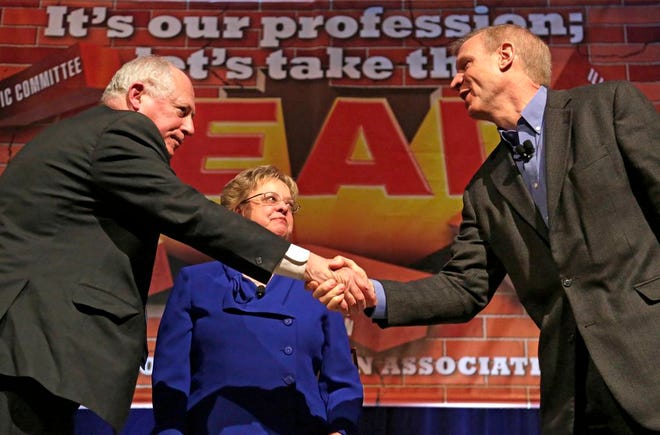 Illinois Gov. Pat Quinn, left, and his Republican rival, Bruce Rauner, shake hands after they appeared together for the first time before the 2014 general election, during the annual meeting of the Illinois Education Association Friday, April 11, 2014, in Chicago. IEA president Cinda Klickna, who moderated the event, stands between them. (AP Photo/M. Spencer Green)