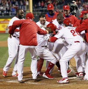 The Philadelphia Phillies surround Jimmy Rollins, center, who hit a solo home run in the bottom of the tenth inning to win a baseball game against the Miami Marlins, Saturday, April 12, 2014, in Philadelphia. The Phillies won 5-4. (AP Photo/Tom Mihalek)