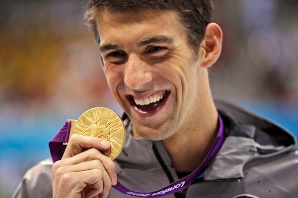 In this Aug. 3, 2012, file photo, United States' Michael Phelps displays his gold medal for the men's 100-meter butterfly swimming final at the Aquatics Centre in the Olympic Park during the 2012 Summer Olympics in London. Phelps is coming out of retirement, the first step toward possibly swimming at the 2016 Rio Olympics. Bob Bowman, the swimmer's longtime coach, told The Associated Press on Monday, April 14, 2014, that Phelps is entered in three events, the 50- and 100-meter freestyles and the 100 butterfly, at his first meet since the 2012 London Games at a meet in Mesa, Ariz., on April 24-26. THE ASSOCIATED PRESS