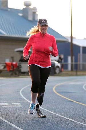 In this April 8, 2014 photo, Boston Marathon bombing survivor Heather Abbott, of Newport, R.I., runs on a track in Middletown, R.I. Besides her special running blade, she has an ìeverydayî leg, and a special prosthetic leg so she can walk in 4-inch heels, her preferred footwear. (AP Photo/Steven Senne)