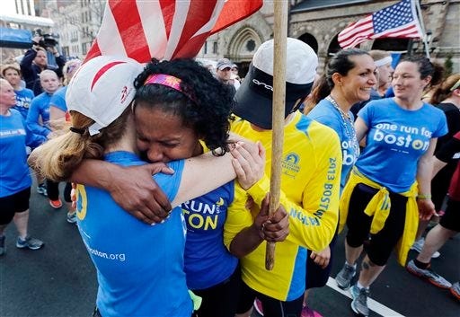 Rosa Evora, center, hugs a fellow participant in a cross country relay that began in March in California and ended at the Boston Marathon finish line in Boston, Sunday, April 13, 2014. Boston Marathon bombing survivors, family members and supporters joined the relay runners for the final half-block to the finish. (AP Photo/Michael Dwyer)