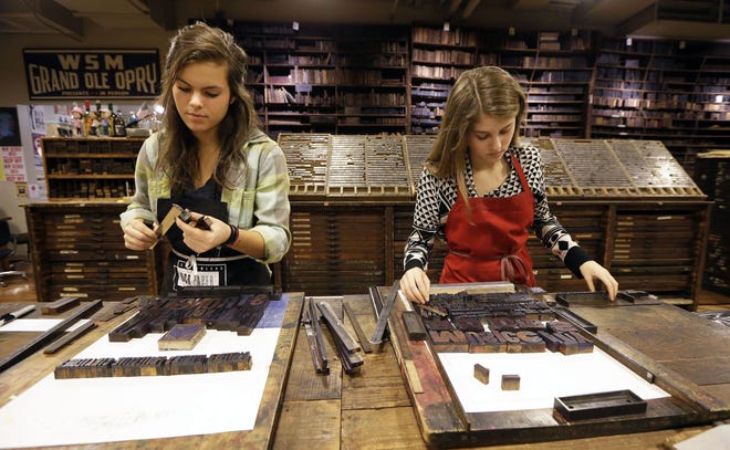 This Jan. 15, 2014 photo shows Lydia Witty, left, and Laura Baisden setting type at Hatch Show Print in Nashville, Tenn. Hatch Show Print, known for its posters advertising the early stars of the Grand Ole Opry, moved into a $100 million expansion of the Country Music Hall of Fame and Museum. (AP Photo/Mark Humphrey)