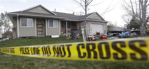 In this April 13, 2014, photo, Pleasant Grove Police police tape is shown in front of the scene where seven infant bodies were discovered and packaged in separate containers at a home in Pleasant Grove, Utah. Authorities say a Utah woman accused of killing six babies that she gave birth to over 10 years told investigators that she either strangled or suffocated the children and then put them inside boxes in her garage. According to a probable cause statement released by police Monday, Megan Huntsman said that between 1996 and 2006, she gave birth to at least seven babies at her home and that all but one of them were born alive.