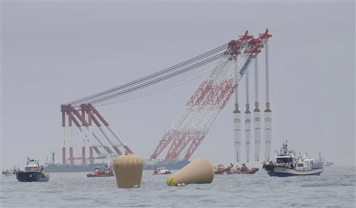 Cranes wait near the buoys installed to mark the sunken ferry Sewol in the water off the southern coast near Jindo, South Korea, Friday, April 18, 2014. Rescuers scrambled to find hundreds of ferry passengers still missing Friday and feared dead, as fresh questions emerged about whether quicker action by the captain of the doomed ship could have saved lives. (AP Photo/Lee Jin-man)