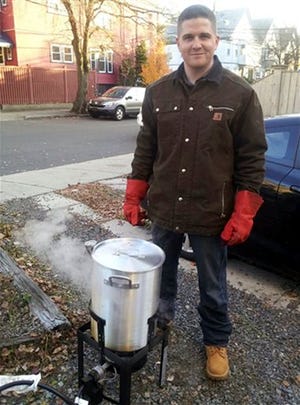 FILE - In this November 2012 file photo provided by Nicole Lynch, her brother, Sean Collier, stands in his driveway in Someville, Mass., frying a turkey for his annual kickball Thanksgiving gathering. Investigators said Collier, a Massachusetts Institute of Technology police officer, was shot to death Thursday, April 18, 2013 on the school campus in Cambridge, Mass., by Boston Marathon bombing suspects Tamerlan and Dzhokhar Tsarnaev in a botched attempt to obtain his gun several days after the twin explosions. Collier will be remembered on the first anniversary of his death in a ceremony at MIT Friday morning, April 18, 2014. (AP Photo/Nicole Lynch)