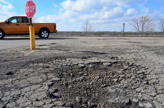 A driver maneuvers past massive potholes in the road at the Beaver Valley Mall in Center Township.