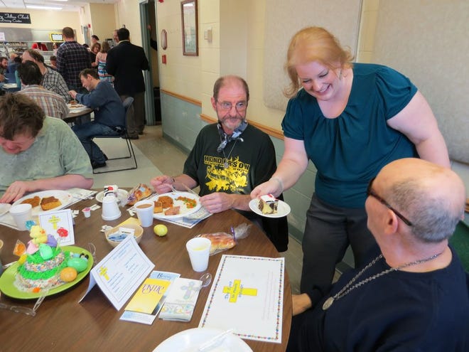 Volunteer Elizabeth Sanner hands a piece of cake to Angelo Gabriel on Sunday at the Rescue Mission of Utica's Easter dinner celebration as Scott Tapley (L) and Tom Wiseham (R) look on. About 250 were served at the event.