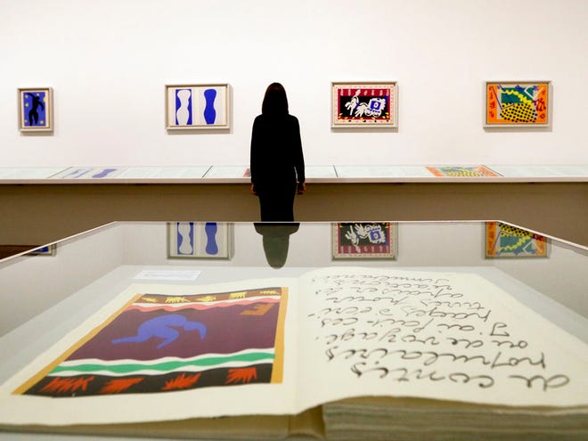 A woman is reflected in a glass cabinet as she looks at artworks by Henri Matisse, on display during a media opportunity at The Tate Modern in London. The artworks are part of the 'Henri Matisse: The Cut-Outs' exhibition that runs at the gallery through Sept. 7.