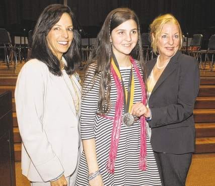 Somerset sixth-grader Lindsey Arruda is presented a Prudential Spirit of Community Awards silver medallion by Catherine Heaney, representing Prudential, as Somerset Middle School Principal Pauline Camara proudly watches. Arruda raised $10,000 designing and selling Boston Strong wristbands and raising $10,000 for 2013 Boston Marathon victims.
