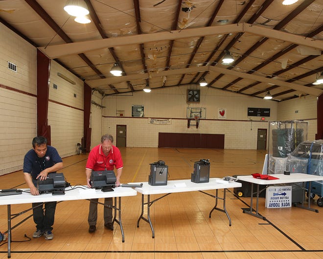 Junior chief technology deputy Rey Que, left, and Supervisor of Elections Mark Andersen set up at the Frank Brown Park Community Building in Panama City Beach on Monday in preparation for today’s elections.