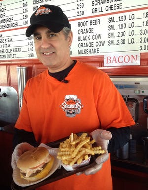 Kirk Xenakis, president and owner of Stewart's Drive-in in Burlington, shows the California Burger we feature in this week's episode of Eat This. Also on the tray is an order of the Golden Krinkle Cut French Fries. photo by Chuck Thomas