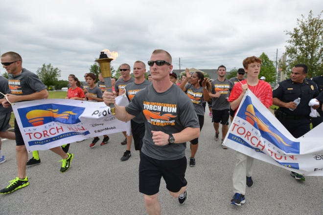 Jonathan Rummel, center, with the Lake County Correctional Institution, carries the torch during the Law Enforcement Torch Run for the Special Olympics Florida in Clermont on Monday.