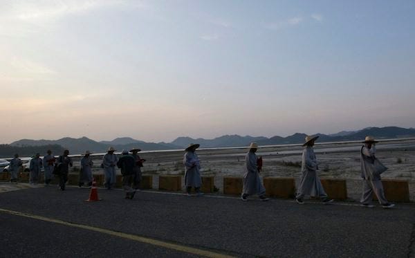 Buddhist monks walk after their pray for safe return of people believed to have been trapped in the sunken 6,852-ton ferry Sewol near the buoys which were installed to mark the vessel in the water off the southern coast, at a port in Jindo, south of Seoul, South Korea, Wednesday, April 23, 2014. The grim work of recovering bodies from the submerged South Korea ferry proceeded rapidly Wednesday, with the official death toll reaching 150, though a government official said divers must now rip through cabin walls to retrieve more victims. THE ASSOCIATED PRESS