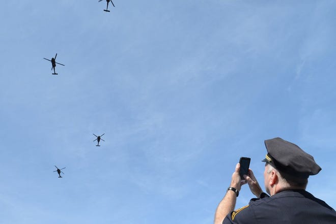 Lieutenant Phil Harrington takes a picture of the Black Hawk helicopters flying over the marathon route in Brookline; April 21, 2014.