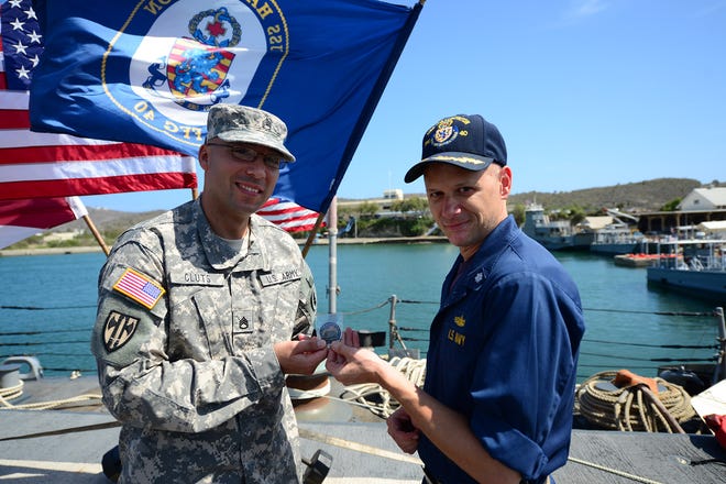 Army Staff Sgt. Christopher Cluts receives a command coin from Cmdr. David Fowler, the commanding officer of USS Halyburton (FFG40), following his re-enlistment aboard the ship at Guantanamo Bay. Halyburton is deployed to the 4th fleet area of responsibility in support of counter illicit trafficking operations.