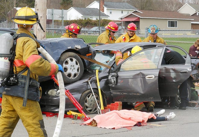 Firefighters work to extract a victim from a car during a mock motor vehicle accident at Frankfort-Schuyler High School on Friday. A student playing the role of a “deceased victim” has a blanket over her as part of the scenario. TELEGRAM PHOTO/STEPHANIE SORRELL-WHITE