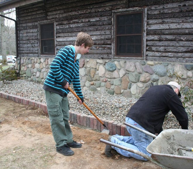 Jonas Ziegler works to complete a service project in order to become an eagle scout. Ziegler, along with family and friends, worked at Bertha Brock Park's Palmer Lodge Monday and Tuesday to remove the wooden edging surrounding the lodge and replace it with bricks.