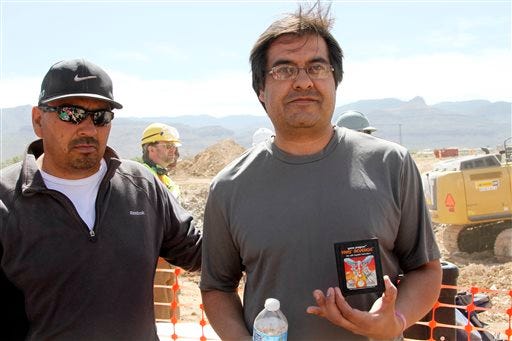 Alamogordo residents Armando Ortega, left, and Raul Ruiz pose for a photograph with a cartridge they found buried in a landfill in Alamogordo, N.M., Saturday, April 26, 2014. Producers of a documentary dug in an southeastern New Mexico landfill in search of millions of cartridges of the Atari 'E.T. the Extra-Terrestrial' game that has been called the worst game in the history of video gaming and were buried there in 1983. (AP Photo/Juan Carlos Llorca)