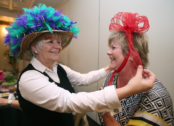 Susan Reynolds, left, helps Ginger Price, right, adjust her hat during the GFWC Greater Ocala Woman's Club monthly general meeting at the Holiday Inn and Suites in Ocala, Fla. on Monday, April 14, 2014. The club is celebrating its 25th anniversary this year.