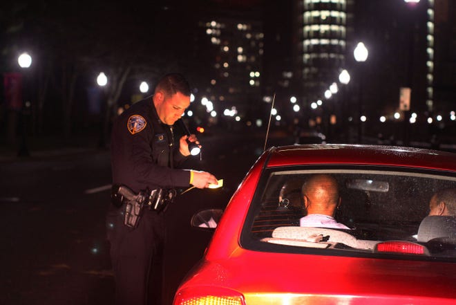 Patrolman Michael R. Troia checks the registration of George F. Daniels Jr. during a stop on April 11. Daniels was charged with DUI.