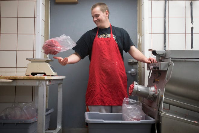 Bradley Bloom tosses a bag of ground chuck onto a scale Wednesday, April 23, 2014, at Pinnon’s IGA Foods in Rockford.